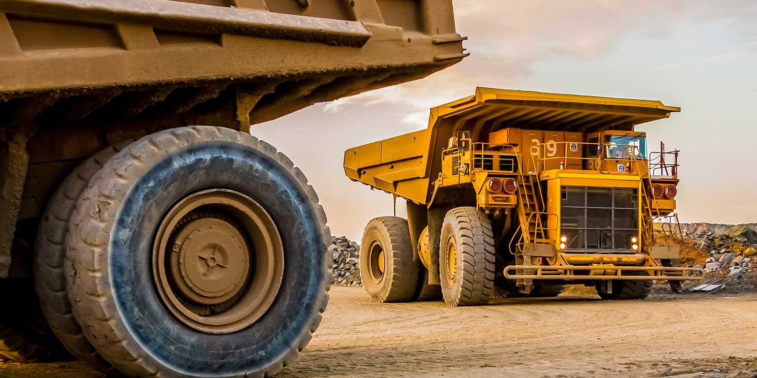 A pair of heavy haul trucks on a South African open cast mine at golden hour